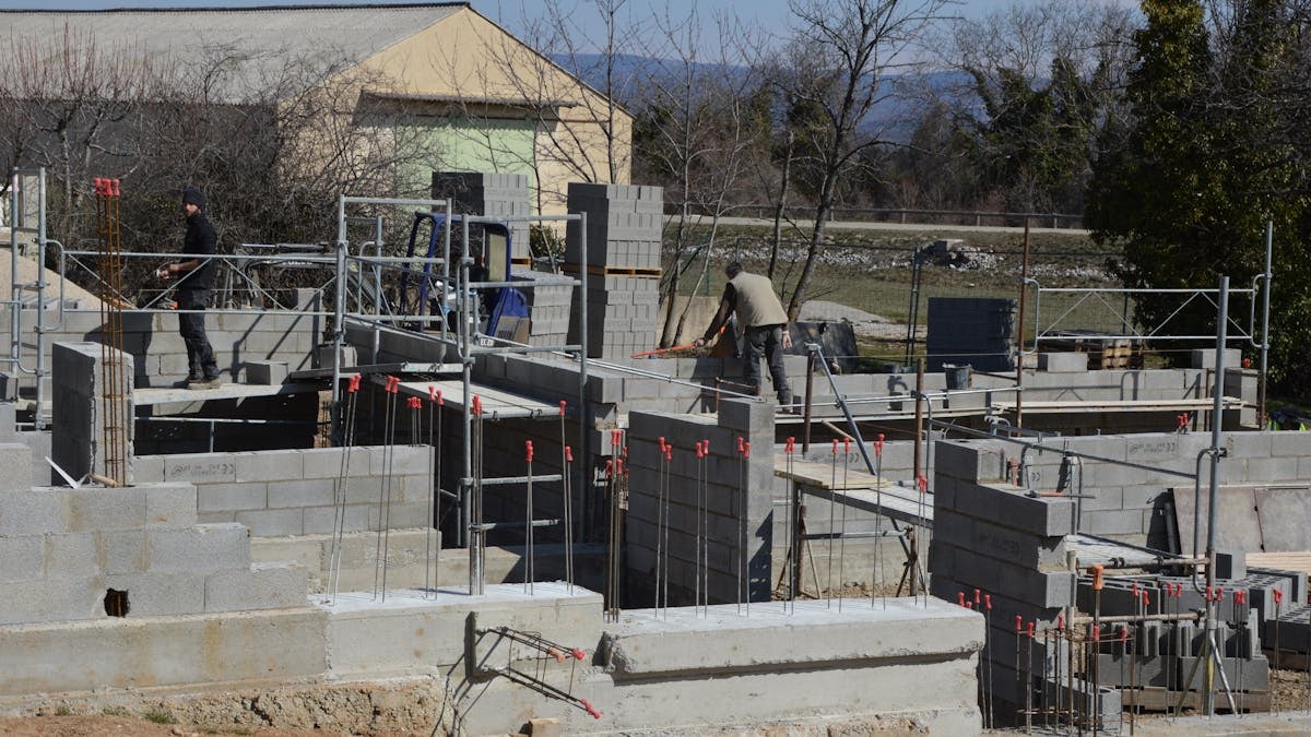 Construction workers building a concrete structure at a sunlit site.